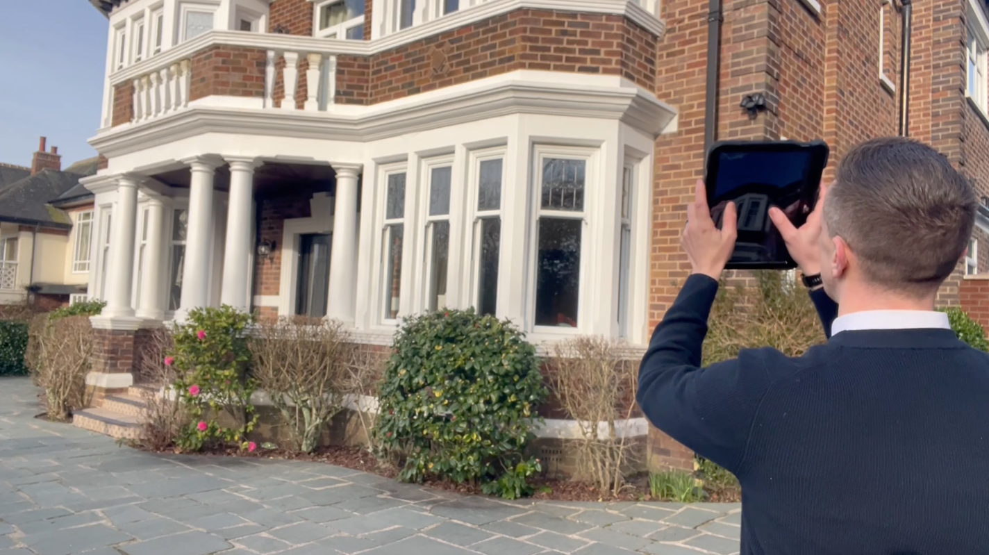 Andrew Raynor, Director of Fylde Coast Chartered Surveyors, taking a photograph of the front of a detached period property